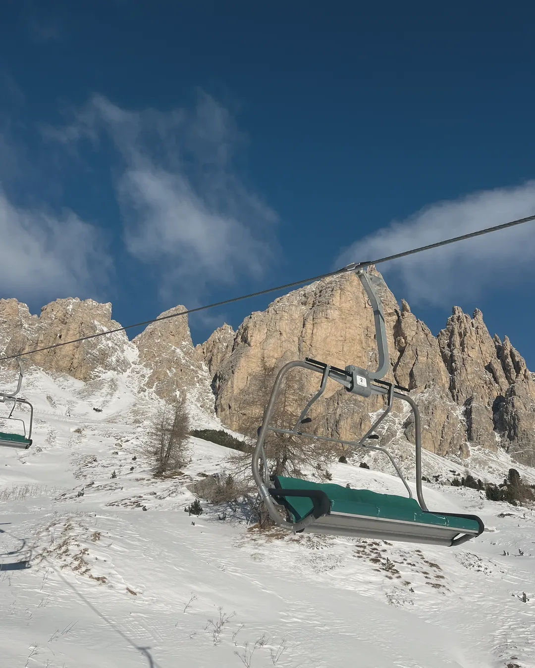 Una seggiovia sopra i pendii innevati, davanti a torri di roccia dolomitica sotto un cielo blu